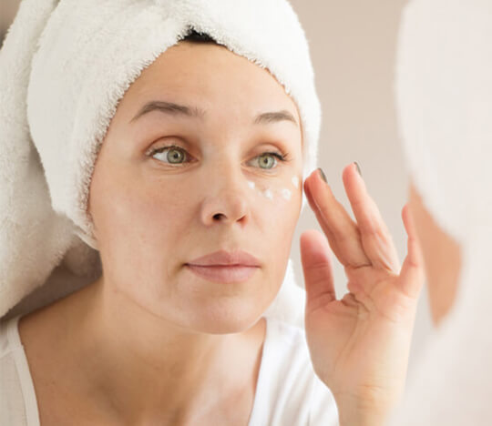 Woman puting cream around her eyes